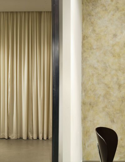 Modern dressing room with a beige curtain, clothes rack with garments, and a seating area with magazines.
